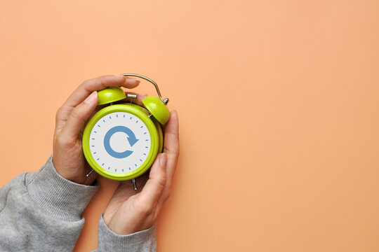 Hands holding alarm clock with refresh icon, restart, reset and fresh start concept