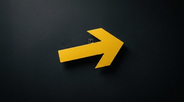 Tilted yellow arrow symbol on black concrete background suggests dynamic movement direction progress choice detour change pathway innovation and creative navigation.