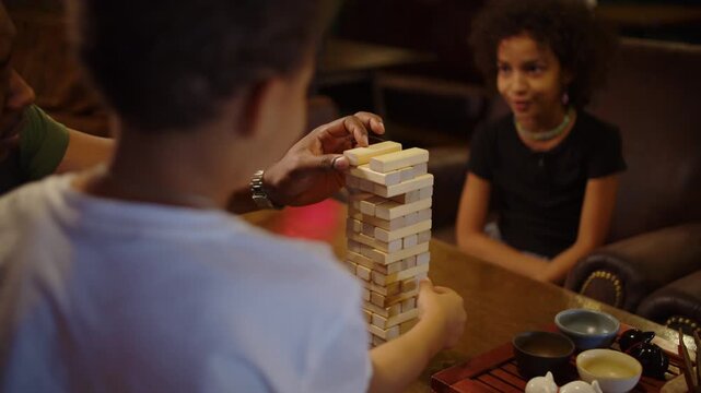 Black father spending quality time with children playing block tower game