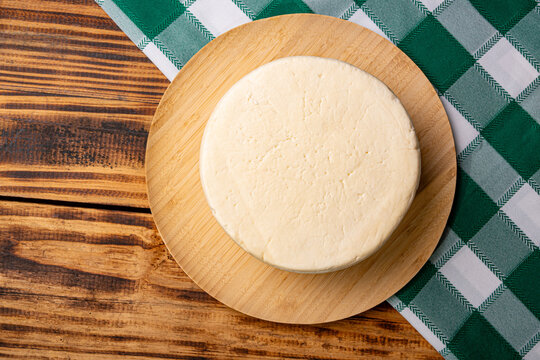 Brazilian "meia-cura" cheese, a delicious semi-cured cheese from Minas Gerais, Brazil, placed on rustic wood against a dark background; selective focus.