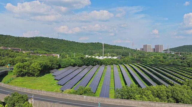 Drone flying forward over solar panels beside a curved highway