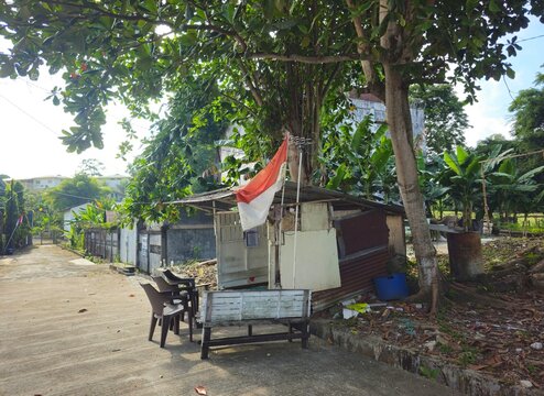 tropical beach hut,Simple roadside stall under leafy tree shade.. Indonesian flag waves gently in morning breeze. Red white flag or Bendera Merah Putih on Independence day                             
