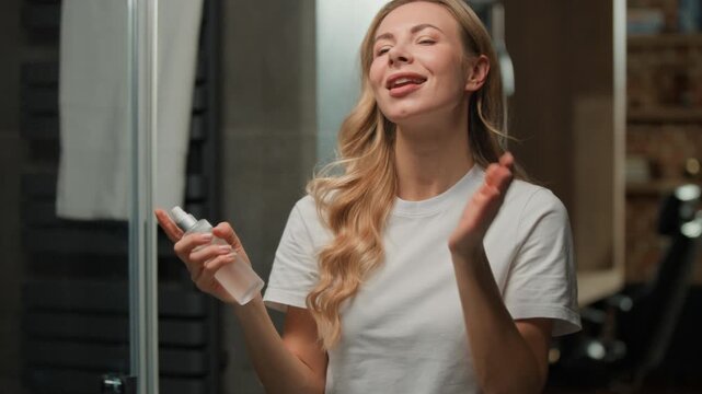 Smiling carefree Caucasian middle-aged woman applying spray thermal water lotion serum toner for face refreshing facial skin happy female smile spraying micellar product beauty routine at bathroom