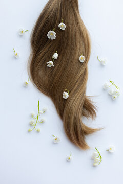 Female hair and lily of the valley flowers. On a white background.