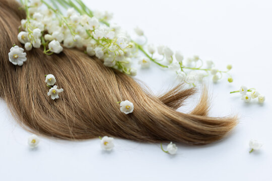 Female hair and lily of the valley flowers. On a white background.