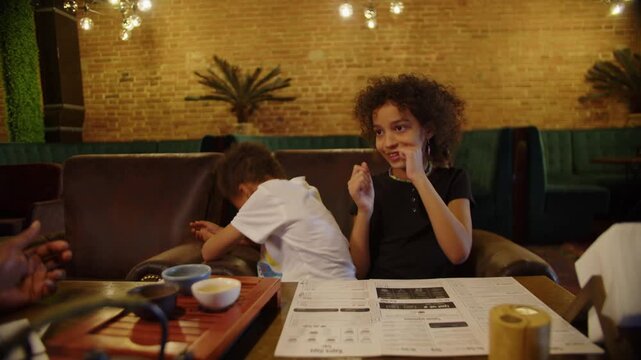 Black brother playfully patting sister on head in cozy cafe