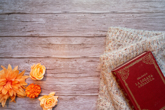 Rustic Composition with Old Book, Knit Scarf, and Flowers on Wood