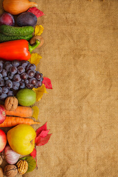 Fresh autumn harvest of vegetables and fruits on burlap vertical background