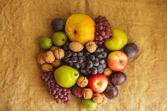 Fresh autumn harvest composition with fruits and nuts on burlap background