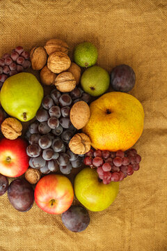 Fresh autumn harvest composition with fruits and nuts on burlap background