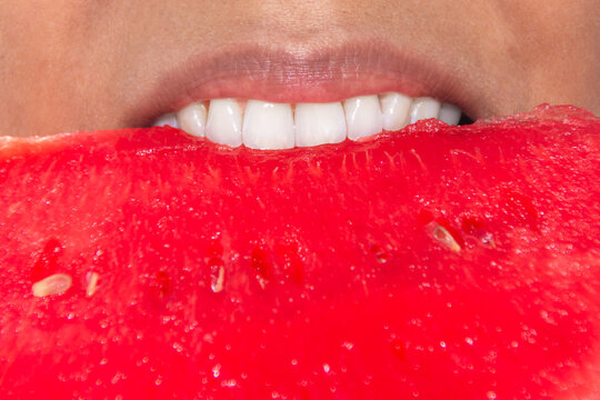 Close up of woman biting into fresh ripe watermelon