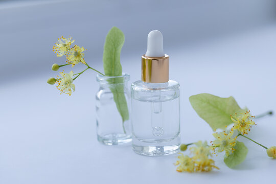 Cosmetic glass bottle with linden flowers.