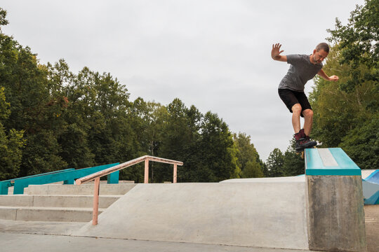 Active middle-aged man performing an aggressive inline skate grind trick on a ledge at a concrete park