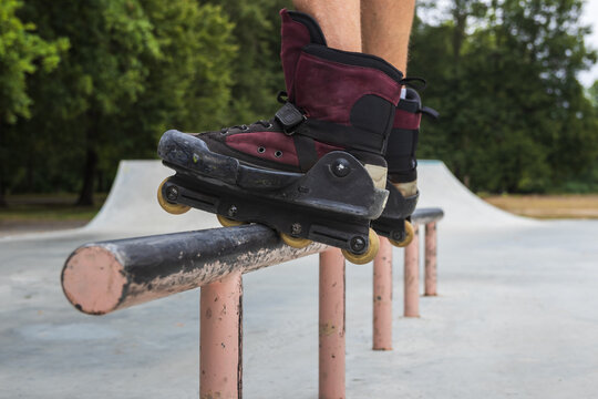 Close-up of aggressive inline skates on a rail during a grind trick by a mature man at a skatepark