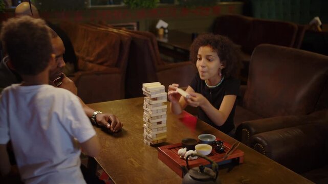 Black father spending quality time with son and daughter playing block tower