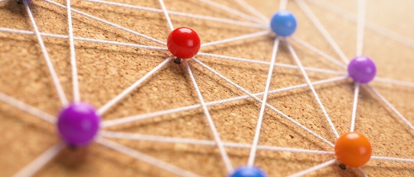 Colorful pushpins connected by strings on cork board illustrating networked ideas