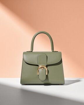 Minimalist green handbag with metallic buckle against soft pastel backdrop