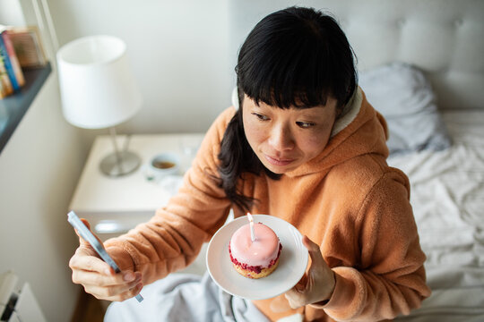 Woman celebrating birthday alone on bed at home