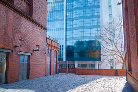 Compound of old style red brick building with modern glass skyscraper on the background. Modern big city design and architecture, restoration of buildings, past and future togetherness concept.