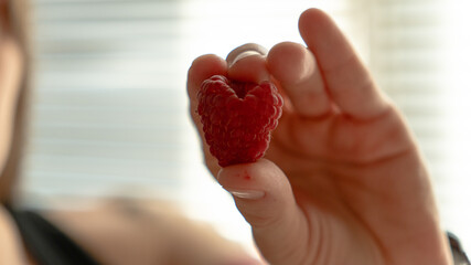 Extreme close-up of fresh red raspberries in a white bowl under warm natural sunlight. © kyrylovasyliev