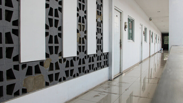 Perspective view of a modern minimalist apartment hallway featuring decorative concrete ventilation roster blocks wall.
