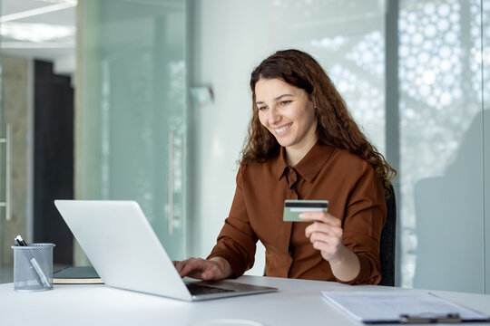 Happy woman shopping online from office, making secure electronic payments with a credit card for e-commerce transactions and experiencing modern banking convenience
