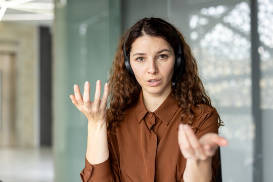 Woman wearing a professional headset during a video conference, making hand gestures while explaining an issue, representing online communication, customer service, or remote work