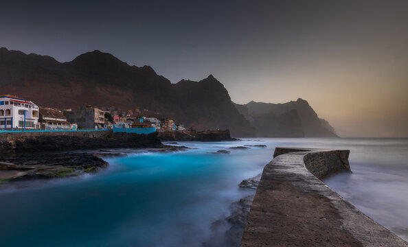 View of the coastal town of Ponta do Sol with its stone pier extending into turquoise waters against the volcanic mountains of Santo Antao in Ponta do Sol, Ribeira Grande, Cabo Verde.