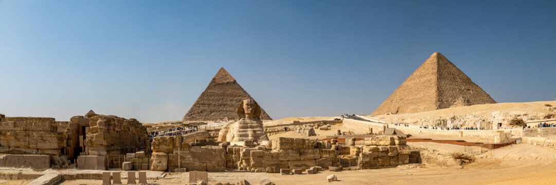 View of the Great Sphinx and the Great Pyramids of Giza standing in the desert landscape under a clear blue sky in Al Haram, Giza Governorate, Egypt.