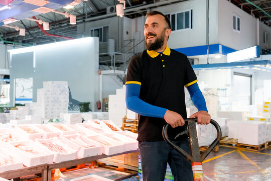 Smiling fishmonger with pallet jack at seafood market
