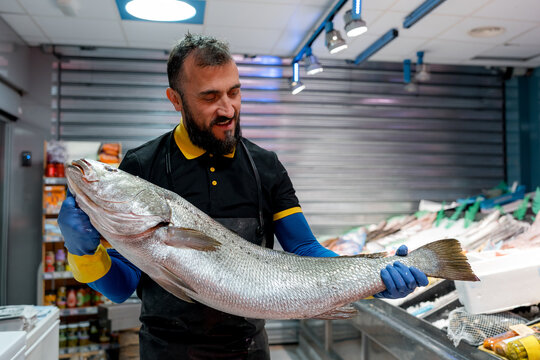 Fishmonger present fresh catch at seafood market counter