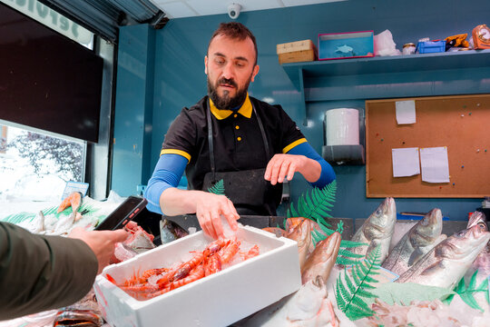 Fishmonger weigh fresh seafood at local fish shop