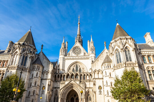 View of the Royal Courts of Justice with its ornate Gothic Revival architecture, pointed arches, and stone spires under a clear blue sky in London, England, United Kingdom.