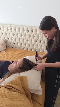 filha fazendo tran&ccedil;as no cabelo da m&atilde;e 