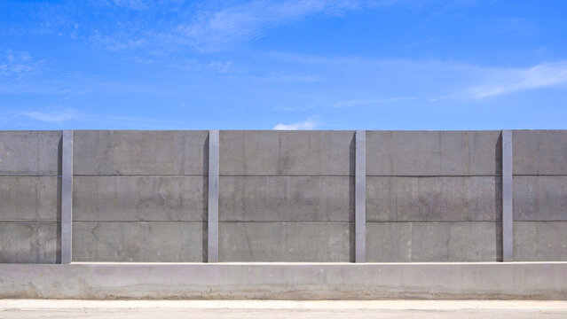 Precast concrete boundary wall panels under bright blue sky. Sturdy industrial barrier, security fence texture, or durable construction project background with copy space.