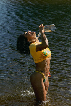 Smiling woman in green and yellow bikini wearing brazilian colors bikini with sun light shining 
