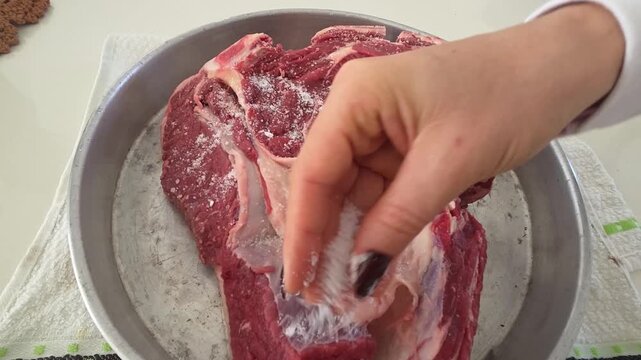 Mulher temperando carne com sal para assar 