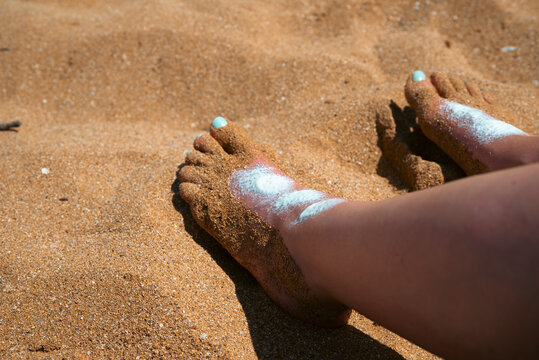 Pies en la arena con crema solar