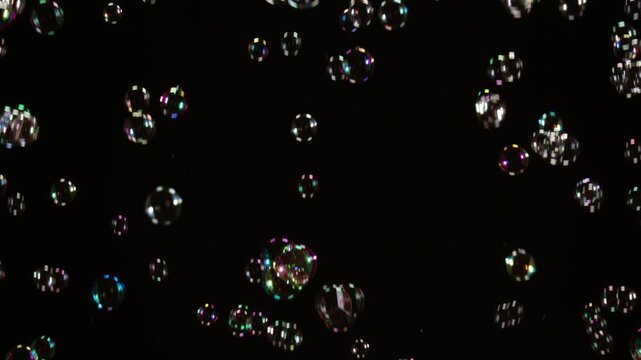Many Soap Bubbles Floating on Black. A large number of soap bubbles moving in one direction against a black background. Great for use in blending