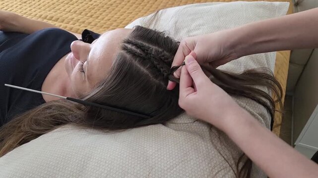 filha fazendo tran&ccedil;as no cabelo da m&atilde;e 