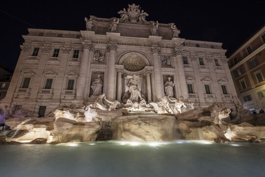 View of the illuminated Trevi Fountain at night with flowing water in Rome, Lazio, Italy.