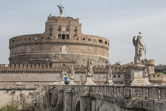 View of Castel Sant'Angelo with its historic circular fortress, the Ponte Sant'Angelo bridge adorned with angel statues, and clear sky in Rome, Lazio, Italy.