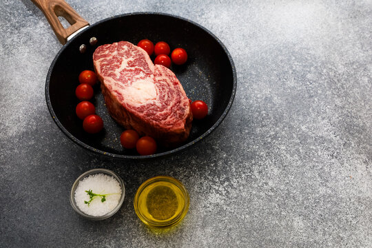 Cooked meat and cherry tomatoes in a pan with salt and oil on table