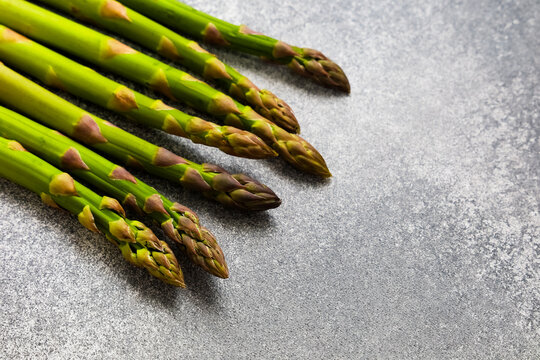 Fresh asparagus arranged on a gray surface showing green spears ready for cooking or preparation