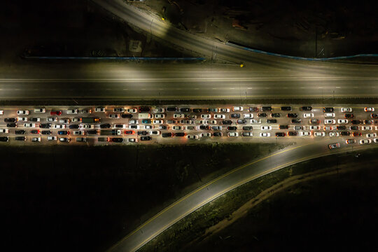 High-altitude aerial view of a massive nighttime traffic jam with hundreds of vehicles on a multi-lane highway.