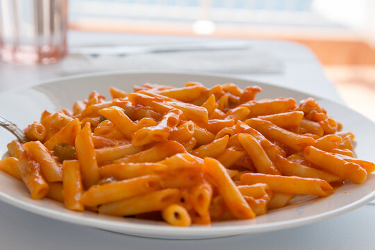 Pasta con salsa di pomodoro e olive verdi su piatto bianco