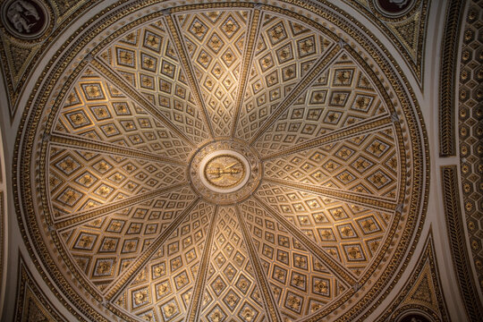 View of the intricate, gilded, geometric dome ceiling with ornate patterns and central medallion in a historic building in Florence, Tuscany, Italy.