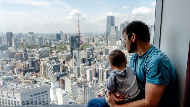 Father and child overlook Minato skyline from window