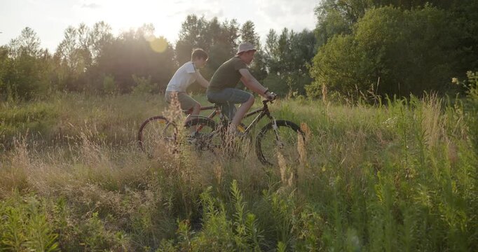 Two boys riding bicycles on nature. Teenagers spending time together. 4K 10-bit