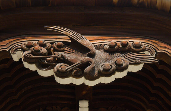 Ornate traditional Japanese wooden carving of a crane bird on a temple entrance.